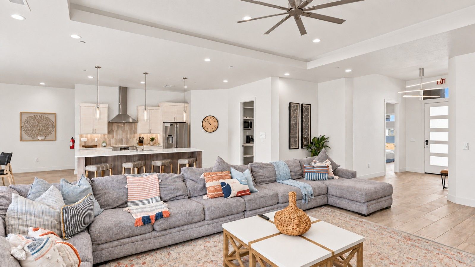 A modern living room with a sectional sofa, a coffee table, and a kitchen in the background.