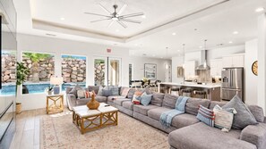 A spacious living area with a sectional sofa, a coffee table, and a view of a pool. - Pecan Valley Oasis | Private Backyard Paradise (Hurricane)