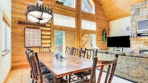 A log cabin interior with a dining table, chairs, a sofa, a TV, and a stone fireplace. - Cozy Log Cabin, Ping Pong, Firepit, Dog friendly! (Arnold)