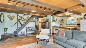 Ein geräumiger Wohnbereich mit Treppe, Sofa, Sessel und Küchenzeile.
