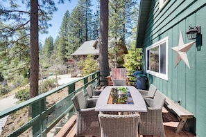 A wooden deck with wicker furniture, a star decoration, and a view of a forested area. - 2 Cabins! Sleeps 17, Ping Pong, Gas Fire Pit & BBQ (Arnold)