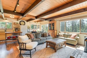 A spacious living area with a wooden ceiling, large windows, a sofa, a chair, and a fireplace. - 2 Cabins! Sleeps 17, Ping Pong, Gas Fire Pit & BBQ (Arnold)