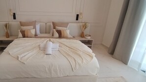 Une chambre spacieuse avec un grand lit, deux tables de chevet et une palette de couleurs neutres.