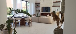 A modern living room with a dining area, a large window, and a fireplace. - Villa de Luxe avec Piscine Privée - Une Oasis d'Exception à Marrakech ". (Marrakesh)