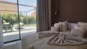Une chambre avec un grand lit, une vue sur l’extérieur et une fenêtre avec des rideaux.