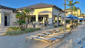 Un hotel con terraza al aire libre, palmeras y una zona de piscina.
