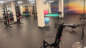 Ett gym med olika typer av träningsutrustning, inklusive styrketräningsmaskiner, lösa vikter och träningsbollar.