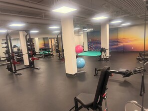 Un gimnasio con diferentes equipos de ejercicio, incluyendo máquinas de pesas, pesas libres y pelotas de ejercicio.
