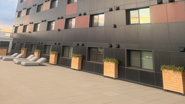 En byggnad med flera våningar och modern design, med en blandning av olika fönsterstorlekar och en slät fasad.