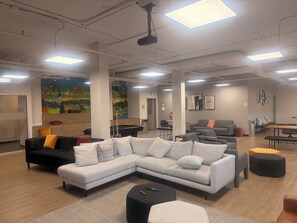 Un área de descanso moderna con un sofá modular, mesa de billar y zona de bar.