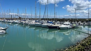 Een jachthaven met tal van zeilboten in de haven, kalm water en een heldere lucht.