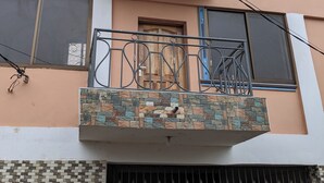 A multi-story building with a balcony, a window with a wooden door, and a gated entrance. - Anna Luxury Lodge - Arusha  (Arusha)