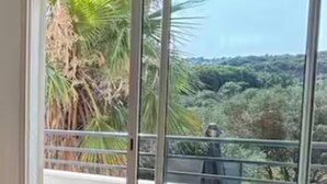 A room with a large sliding glass door leading to a balcony with a view of greenery and hills. - La salamandre Pavilion facing the golf course (Juvignac)