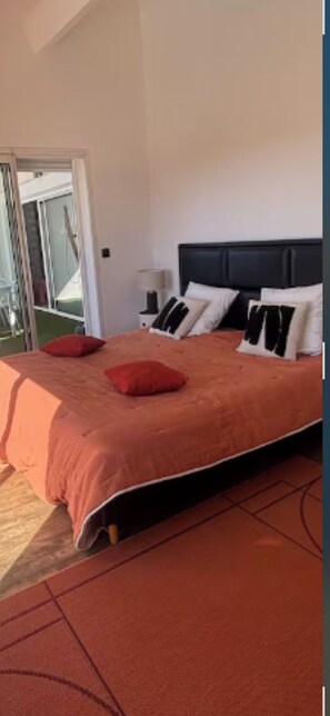 A bedroom with a bed, pillows, a nightstand, and a view of the outdoors. - La Salamandre Pavilion with a view of the golf course (Juvignac)