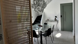 A modern dining area with a glass table, black chairs, a decorative metal light fixture, and a staircase. - La salamandre Pavilion facing the golf course (Juvignac)