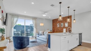 Uma sala de estar moderna com sofá, mesa de jantar e área de cozinha com ilha central.