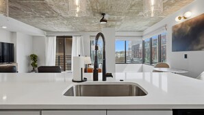 A modern kitchen with a central island, stainless steel sink, and pendant lighting. - Summit Hill Stay | King Suite | Free Parking (Knoxville)