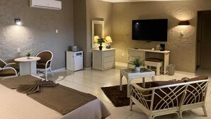 A hotel room with a bed, a TV, a desk, a chair, a small table, a lamp, and an air conditioning unit. - Hotel Casa Layun (Cordoba)