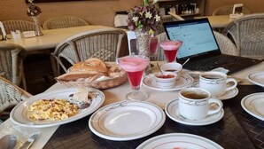 A dining table set with plates, glasses, a laptop, and a basket of bread. - Hotel Casa Layun (Cordoba)