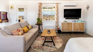 Una sala moderna con sofá, mesa de centro, televisor y vista al desierto.