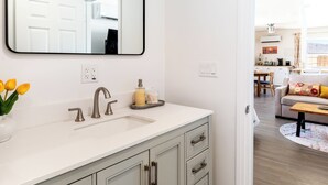 Un baño con tocador blanco, un espejo grande y un lavabo.