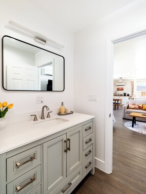 A bathroom with a white vanity, a large mirror, and a sink.