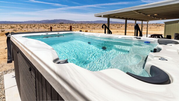 Un jacuzzi en un entorno exterior con un paisaje desértico al fondo.