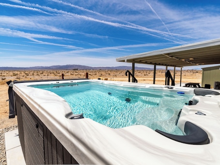 A hot tub in an outdoor setting with a desert landscape in the background.. A desert sanctuary in Wondervalley to stargaze and escape the city