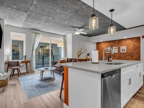 A modern kitchen with a central island, a dining area with a round table, and a sofa. - The Summit Nest | Cozy 1BR in the Heart of Knox (Knoxville)