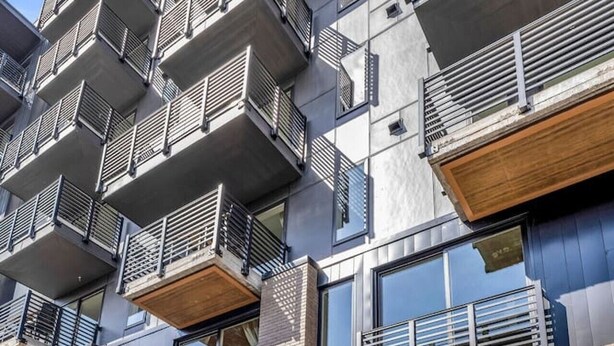 Een modern meerlaags gebouw met balkons, grote ramen en een plat dak.