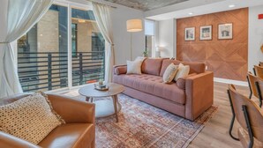 Een moderne woonkamer met een bank, salontafel en stoelen, een balkon met een leuning en een plafondventilator.