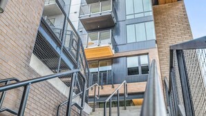 Una escalera conduce a un edificio moderno de varios pisos, con una combinación de ladrillo y vidrio.