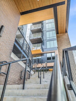 Eine Treppe führt zu einem mehrstöckigen Gebäude im modernen Stil, das Ziegel und Glas kombiniert.