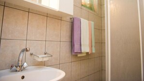 Un baño con lavamanos, espejo y zona de ducha.