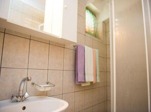 Ein Badezimmer mit Waschbecken, Spiegel und Duschbereich.