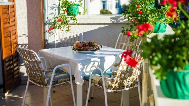Un patio al aire libre con una mesa y sillas, una planta en maceta y una ventana con vistas.