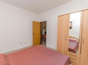 Ein Schlafzimmer mit Bett, Kleiderschrank und einer Tür zu einem weiteren Raum.