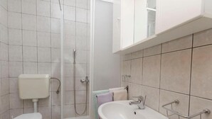 Ein Badezimmer mit Toilette, Dusche, Waschbecken und Fliesenwänden.
