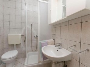 Ein Badezimmer mit Toilette, Dusche, Waschbecken und Fliesenwänden.