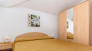 Ein Schlafzimmer mit einem Bett, einem Nachttisch, einer Lampe, einem Kleiderschrank und einem Wandbild.
