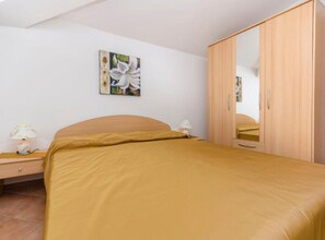 Ein Schlafzimmer mit einem Bett, einem Nachttisch, einer Lampe, einem Kleiderschrank und einem Wandbild.