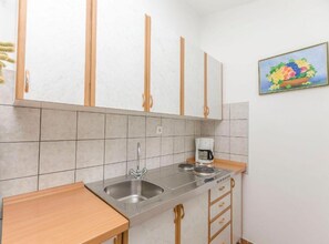 A kitchen with a double sink, a coffee maker, and wooden cabinets. - Classic One Bedroom Apartment with Terrace (Vodice)
