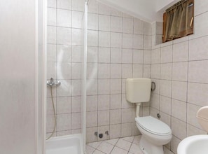 A bathroom with a shower, toilet, and a window with curtains. - Classic One Bedroom Apartment with Terrace (Vodice)