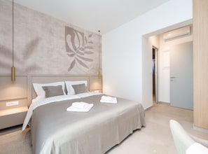 Ein modernes Schlafzimmer mit einem großen Bett, Nachttischlampen und einem Wandbild.