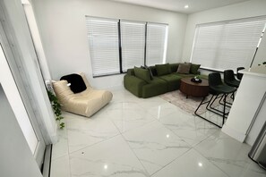 Una sala de estar moderna con un sofá modular, una mesita redonda y un sillón tipo puff.