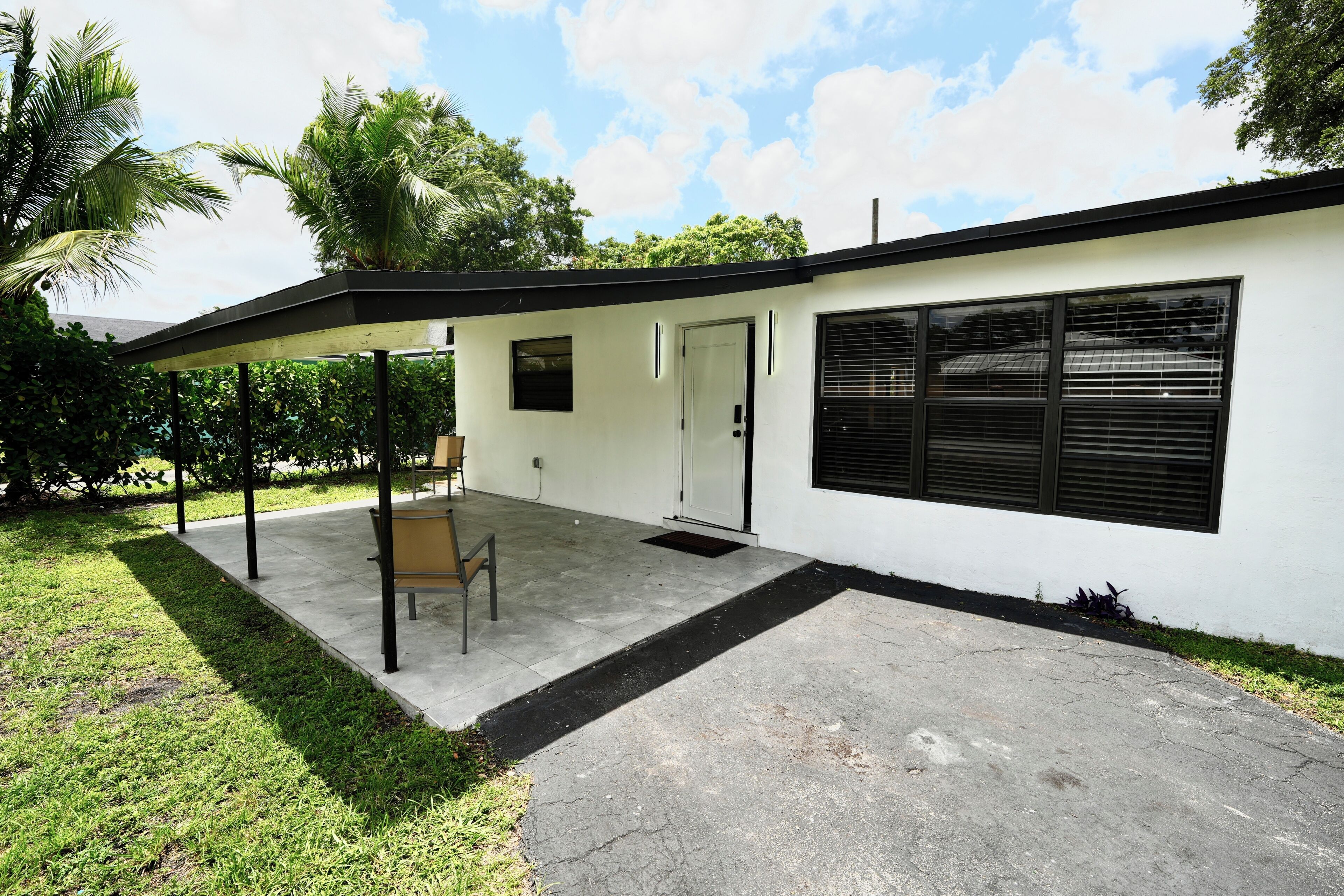 A modern building with a covered patio, a door, and a window with blinds.