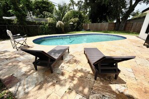 A backyard with a swimming pool, two lounge chairs, and a wooden fence. - 6370 Atlanta House (Hollywood)