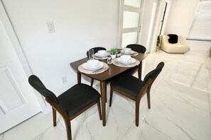 Un comedor con una mesa dispuesta para cuatro, incluyendo platos, tazones y vasos.