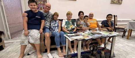 Un grupo de personas sentadas en un sofá y una mesa con libros y un florero.