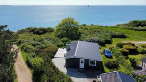 Una casa con tetto spiovente, vialetto in pietra e vista sul mare.